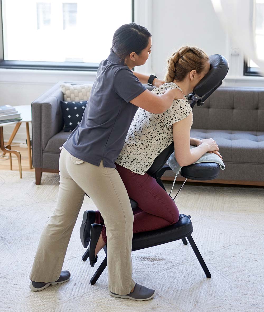 A LoDo massage therapist stretching the arm of a client seated in a massage chair
