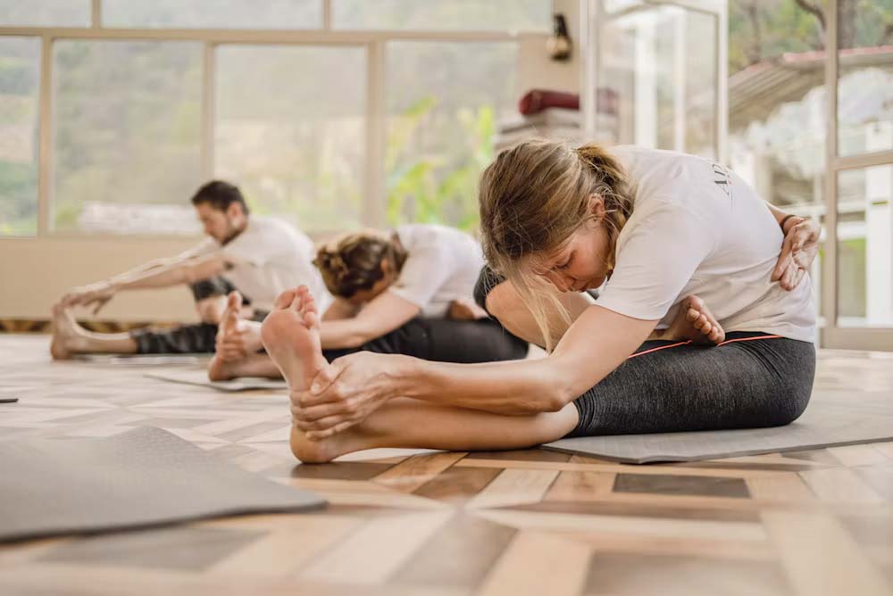 A LoDo instructor leading a seated twist on office chairs, with three employees following along behind her